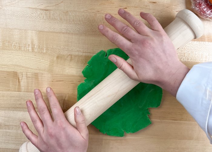 Image of Roll out the green ball of dough to 1/4 inch. Our Perfect Cookie Rolling Pin takes the guesswork out of this step--its fixed depth handle results in perfectly 1/4 inch cookies every time for even baking.