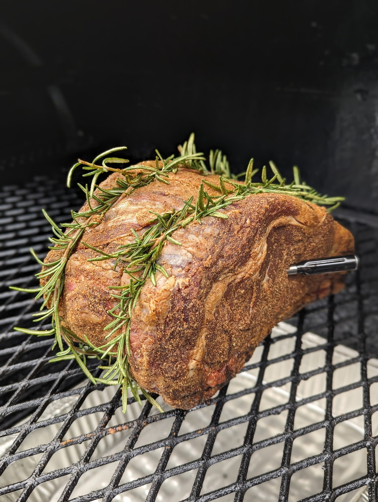 Image of Thread some rosemary sprigs along the butcher's twine, making sure to reserve 4-5 to make a basting mop.  Put beef tallow and garlic cloves in a foil tin and place in the smoker.