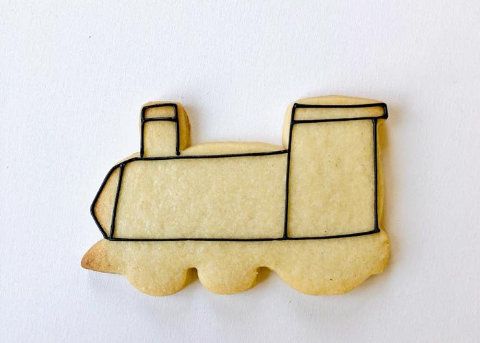 Image of Using piping consistency black icing, outline the body of the train as shown. Create some additional definition in the cab of the train, the front, and the smoke stack to add dimension to your cookie.