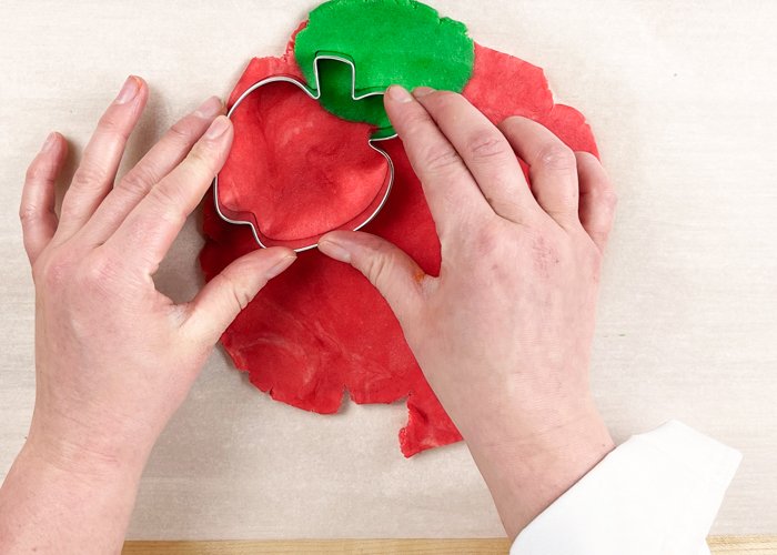 Image of Using the apple cookie cutter, cut out your cookies, positioning the cutter so that the green is at the top, encompassing the leaf and stem. You can reform the dough and roll it out as needed.