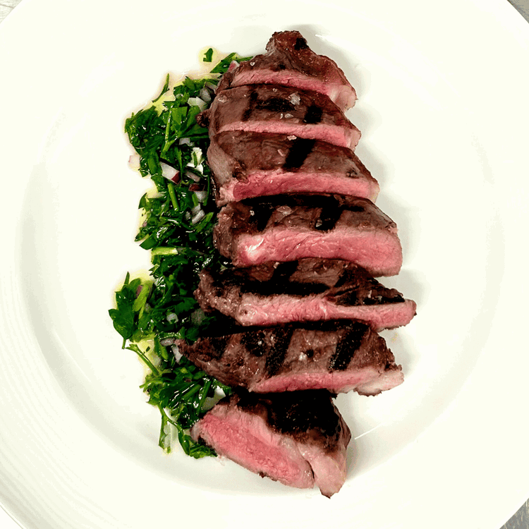 Image of Slice the rested Bison New York Strip into succulent portions and elevate its taste with a generous drizzle of chimichurri. The combination of the perfectly grilled steak and the vibrant chimichurri creates a symphony of flavors that will leave your...