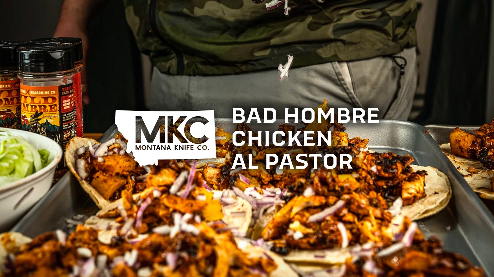 A sheet pan holds rows of corn tortillas cradling perfectly seasoned and tender chicken al pastor.