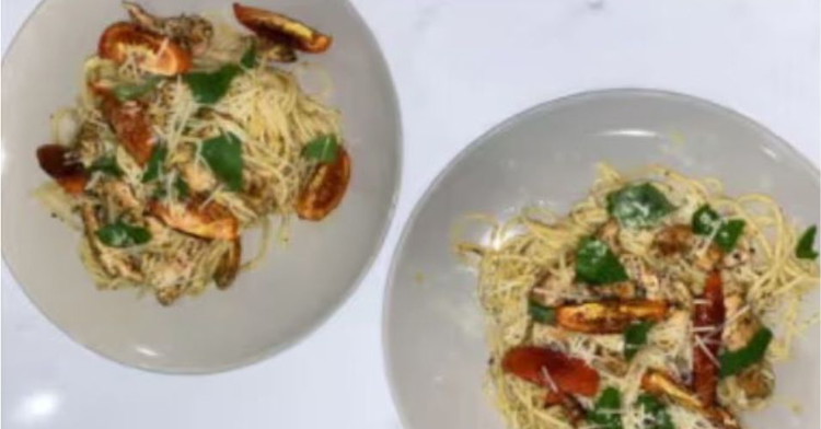 Image of Plate pasta between 2 bowls and top with roasted tomato wedges. Top with remaining parmesan and serve.  Optional: Tear fresh basil leaves for garnish.