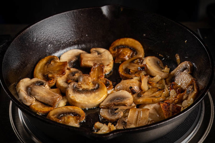 Image of Heat the oil in a large skillet
over medium heat. Add the garlic and mushrooms with a
pinch of salt and cook until golden brown, about 5-7 minutes.