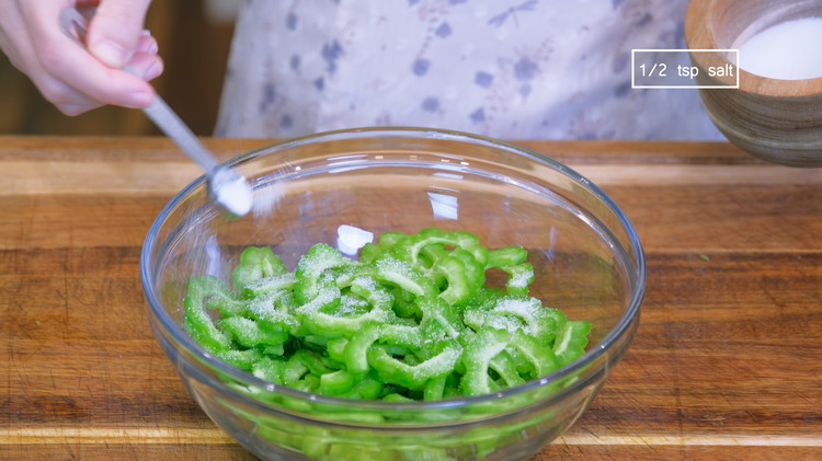 Image of Season the bitter melon with 1/2 tsp of salt and toss it thoroughly. Let it sit for 15 minutes to allow the salt to draw out some moisture.