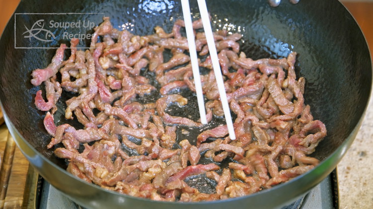 Image of Add the marinaded beef and use a pair of chopsticks to loosen the strips so they don’t tangle together. Stir over high heat for 1-2 minutes or until the meat has changed color.