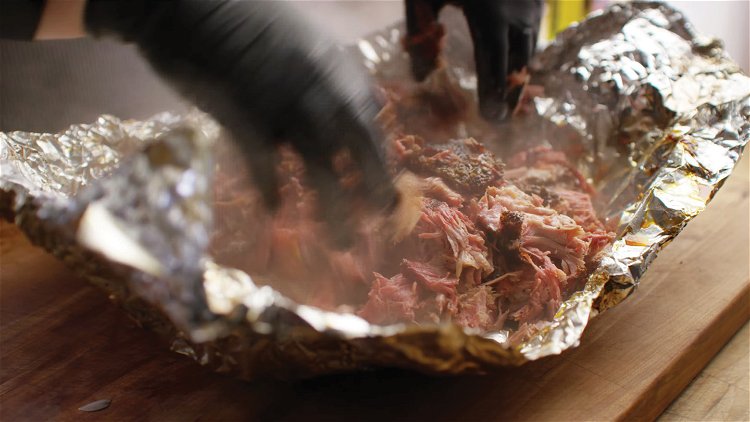Image of Shred the pork butt by hand using knit gloves covered...