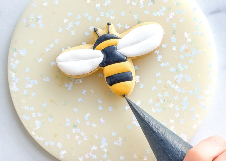 Image of Pipe a small black dot at the bottom of the bee and use your scribe tool or toothpick to drag it out to form the bee’s stinger.  