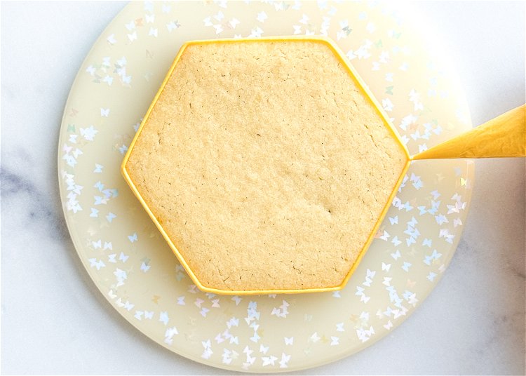 Image of Using the yellow outline consistency icing, outline the cookie shape.  