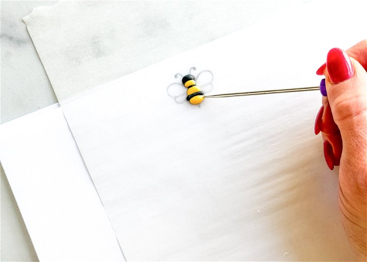 Image of Using the yellow outline consistency icing, pipe over the sections of the bee image that are yellow. Let this icing dry for at least 10-15 minutes before moving onto the next step.  
