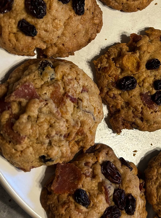 Brown Bacon Breakfast Cookies spotted with raisins and bits of bacon on a cutting board.  