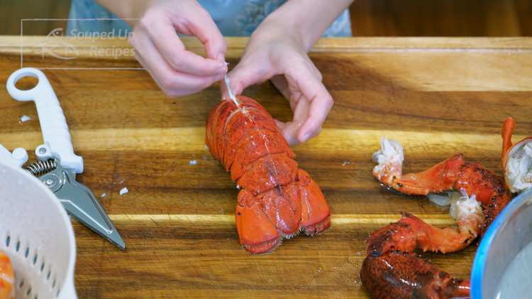 Image of Detach the the lobster tail from the head by twisting it. Take a pair of scissors and cut the back open. Remove the vein and set the lobster tail aside.