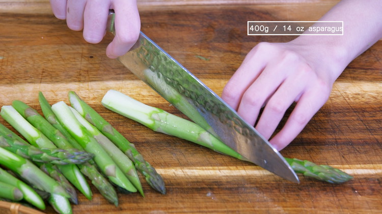 Image of Use a vegetable peeler to peel the stringy and fibrous skin at the end of each asparagus. Then, cut the asparagus into 2.5-inch long stalks.