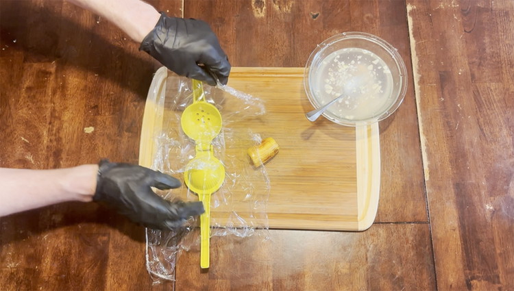 Image of Cut 2 pieces of plastic wrap around 6 inches. Place each piece on both sides of an open lemon squeezer.