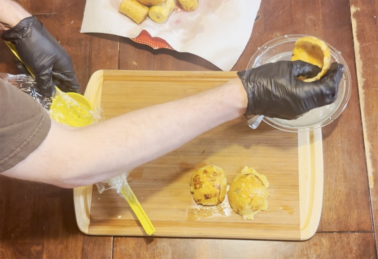 Image of Remove plantain from the squeezer and dip into the bowl with water, garlic, salt and lime. Then remove with the bowl side facing downward to drain. Repeat with the remaining plantain pieces.