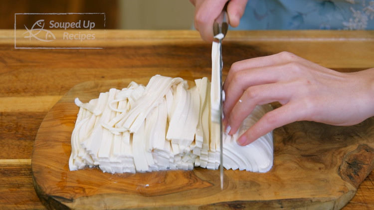 Image of While waiting, cut the tofu into 1/4-inch thick slabs. Push the slabs to one side, then julienne them into strips. I am using silken tofu because I love its smooth texture. However, firm tofu also works.