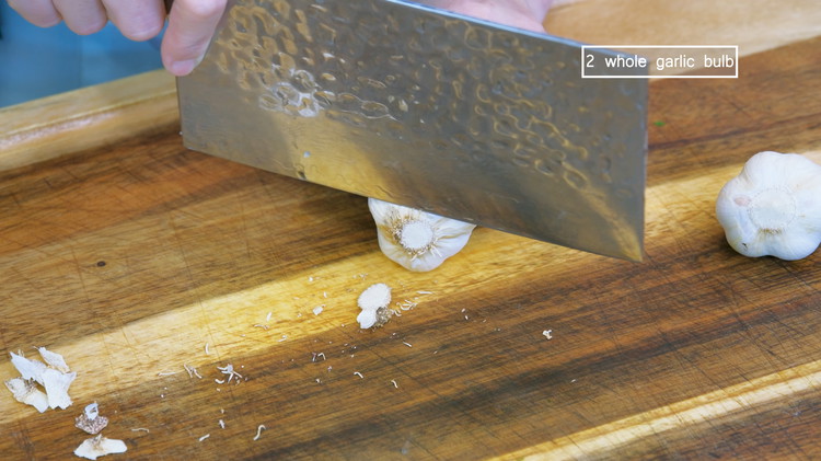 Image of Use a knife to carefully remove the messy root from the garlic bulbs. We are going to cook the entire bulb in the soup so we don’t want any of the dirty roots.