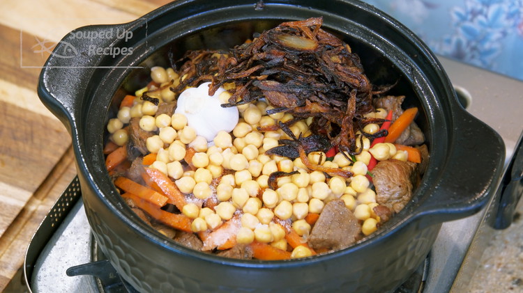 Image of Add cumin powder, sweet paprika, salt, the soaked chickpeas, garlic bulbs, Thai bird-eye chilies, and browned onions.