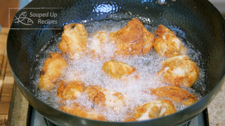 Image of Use a sieve to eliminate the crispy bits from the oil. Increase the oil’s temperature to 400F. Add all the chicken wings back. Fry for 2-3 minutes or until golden brown.