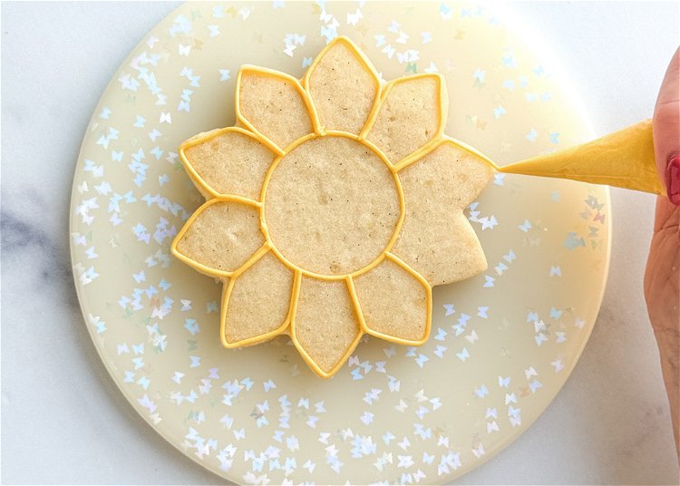 Image of Continuing with the yellow outline consistency icing, pipe each flower petal as shown in the photo.  