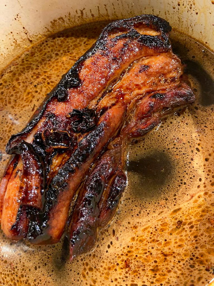 Image of Chashu (Kakuni-Variante)Einen Topf mit Deckel verwenden, in den der Schweinebauch gerade so passt. Schweinefett in den Topf geben, schmelzen lassen und das Fleisch von beiden Seiten etwa 4 Minuten pro Seite anbraten.Fleisch aus dem Topf nehmen und beiseite legen. Knoblauchzehen...