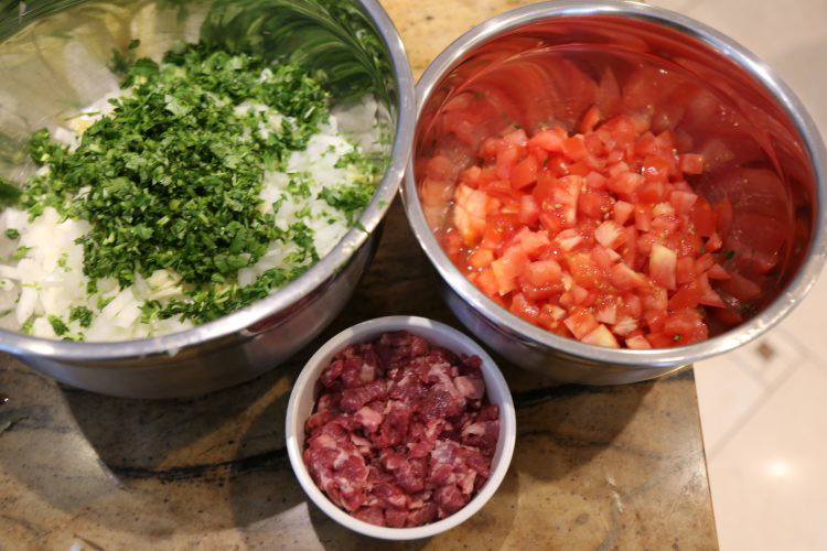 Image of This recipe is going to really test your knife skills. Or rather, help you practice them. You have a pile of tomatoes and onions to cut up in addition to a whole bunch of cilantro and lamb to cut into...