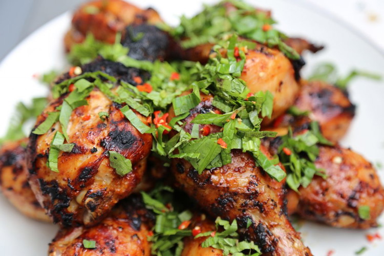 Image of Once the chicken looks beautiful and is fully cooked remove it from the grill and top with roughly chopped culantro, mint, and a chopped fresh Thai chili for some color and fresh heat.