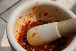 Image of Roughly chop the Thai chilies and garlic and place inside a stone mortar with the sugar. Grind with pestle until a mostly smooth or chunkyish paste has formed. Add remaining fish sauce and soy sauce and mash in a mortar to form...