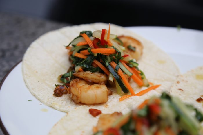 Image of To build your tacos, first add the shrimp, then some slaw on top. Add more peanuts and scallions to finish it off.