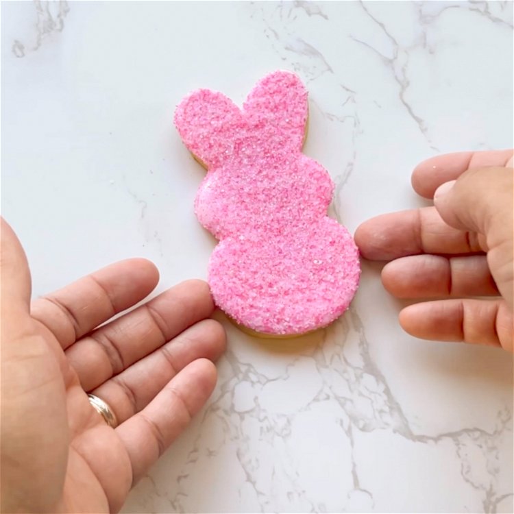 Image of Hold the bunny by the edges so as not to disturb the sanding sugar coverage, and gently place on a flat decorating surface. 