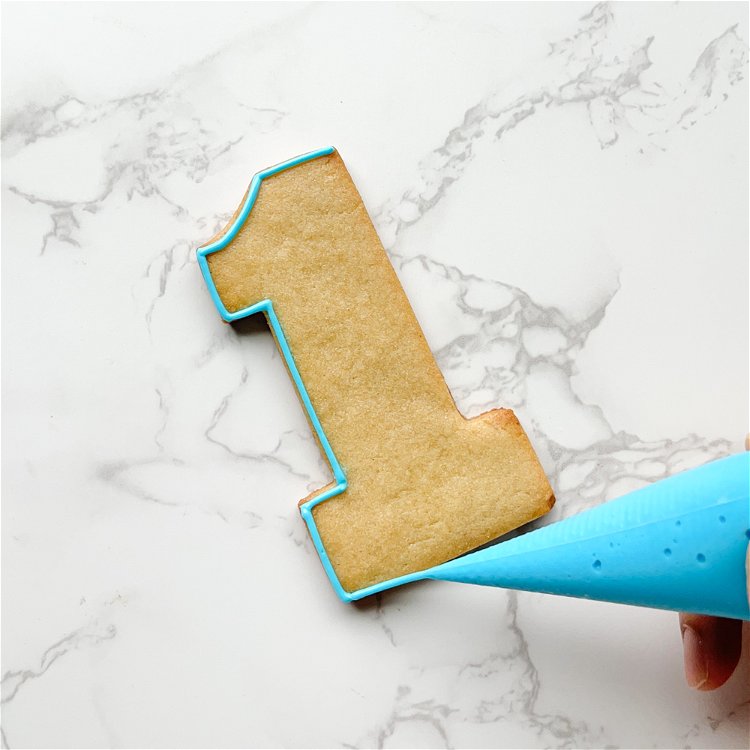 Image of For neat outlining, hold the tip of the piping bag slightly above the shape, letting the icing fall into place on the cookie.