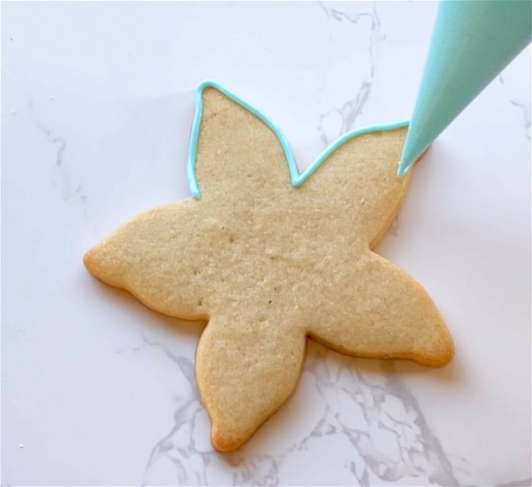 Image of For neat outlining, hold the tip of the piping bag slightly above the shape, letting the icing fall down into place on the cookie. 