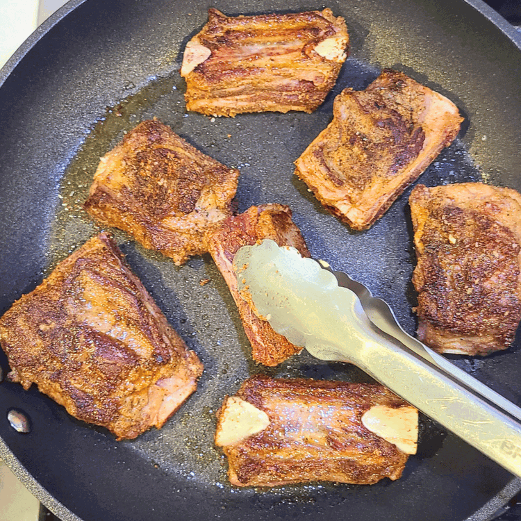 Image of Heat fat or oil in a heavy bottom skillet over medium-high heat, sear the ribs on each side 