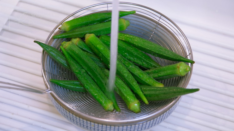 Image of Take the okra out of the pot and rinse under running water to cool completely so your hands can handle it.