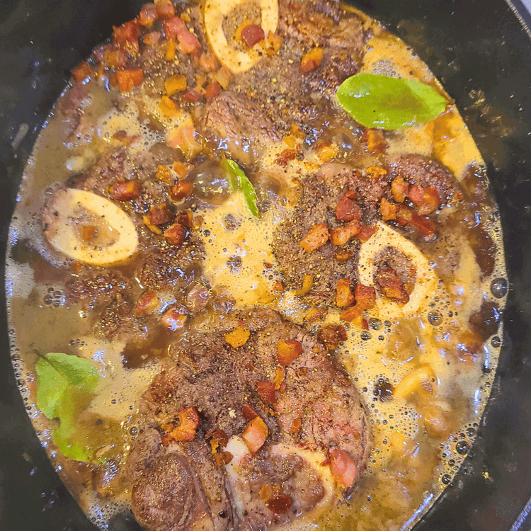 Image of Return the bison and the pancetta to the pan. Add 1 tbsp of white wine vinegar and then add enough broth to come up to the top of the shanks.