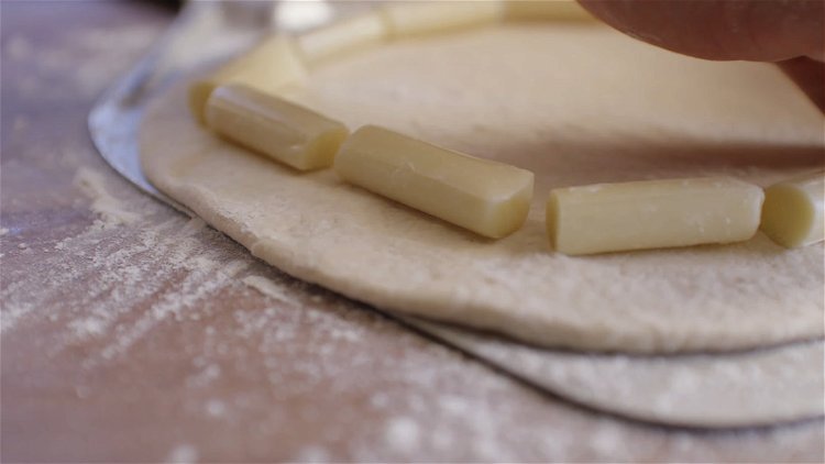 Image of Roll the dough out with a rolling pin. Divide cheese...