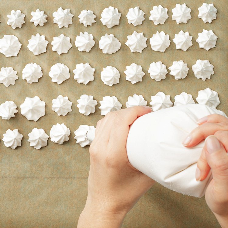 Image of Gently add the meringue mixture to a piping bag fitted with a large star tip. Pipe cookies on a baking sheet lined with parchment paper or a silicone mat.