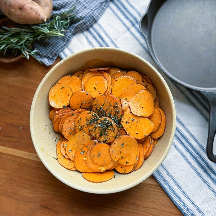 Image of In a bowl, toss the sliced sweet potatoes, pressed garlic,...