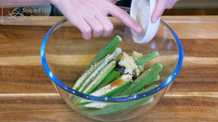 Image of Season the okra with 1/4 tsp of salt, 1.5 tsp soy sauce, 1.5 tsp oyster sauce, some ground black pepper to taste, and the grated garlic. Mix well until you see the sticky liquid pulling in between the pods.