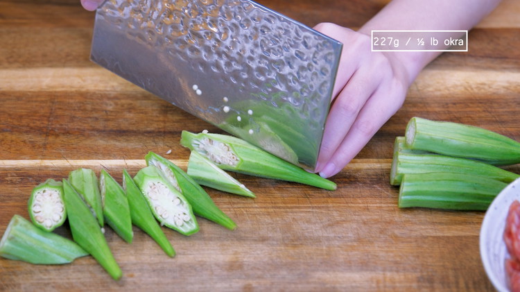 Image of Cut of the calyx of the of okra, then cut each pod into three pieces at a 45-degree angle and set it aside.