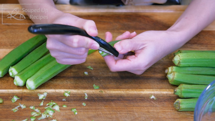 Image of Use a peeler to peel the tough calyx of the okra and keep the pods whole. We will not cut open the pods, otherwise the okra will become dry after air frying.
