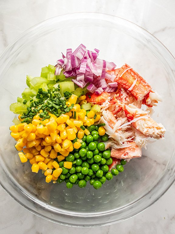 Image of Add celery, peas, corn, red onion, and chives to bowl...