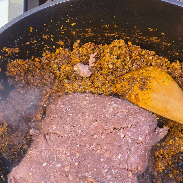 Image of Add in your meat and break it up with a wooden spoon.