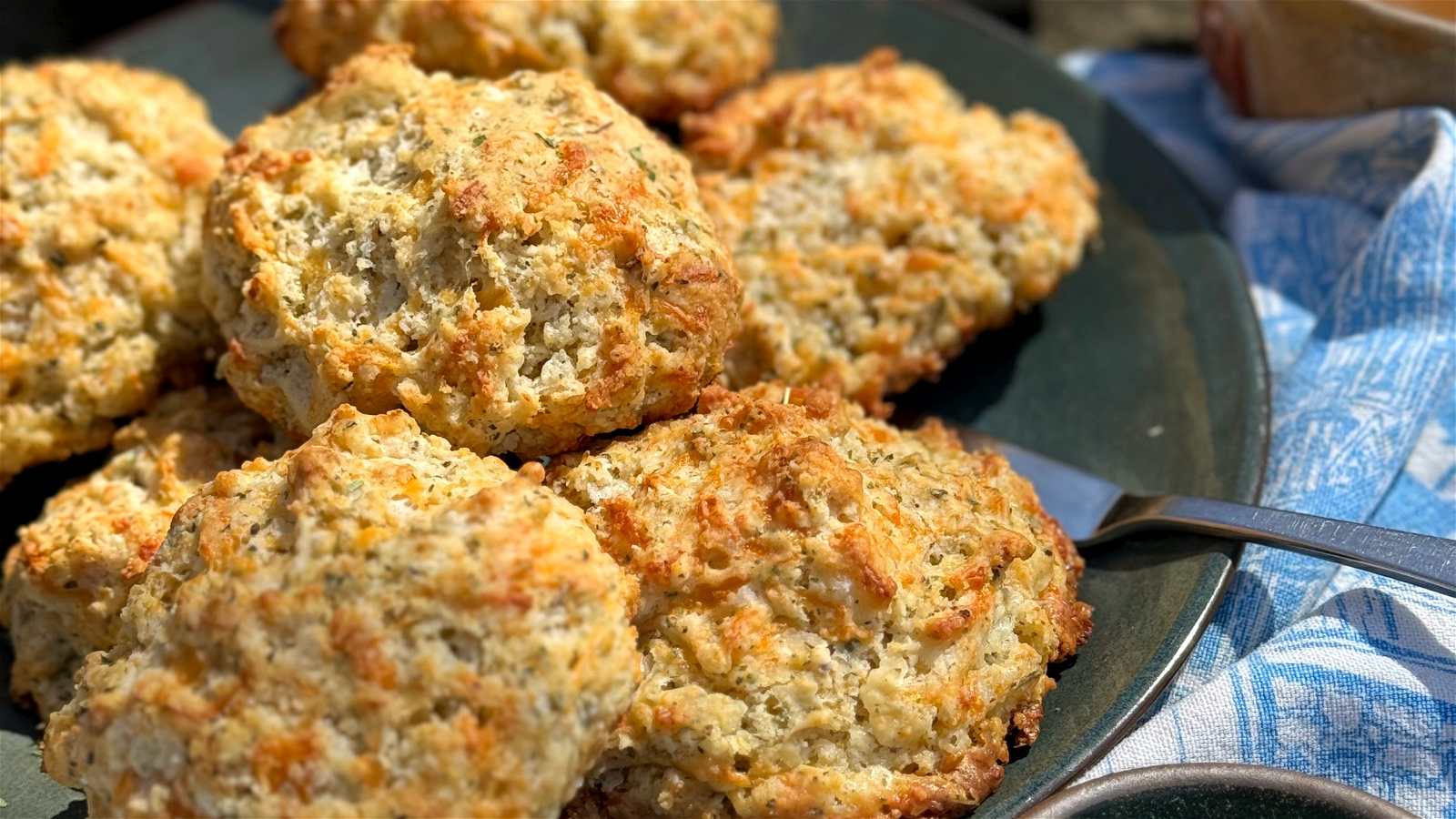 golden brown biscuits with cheddar and herbs on a green plate