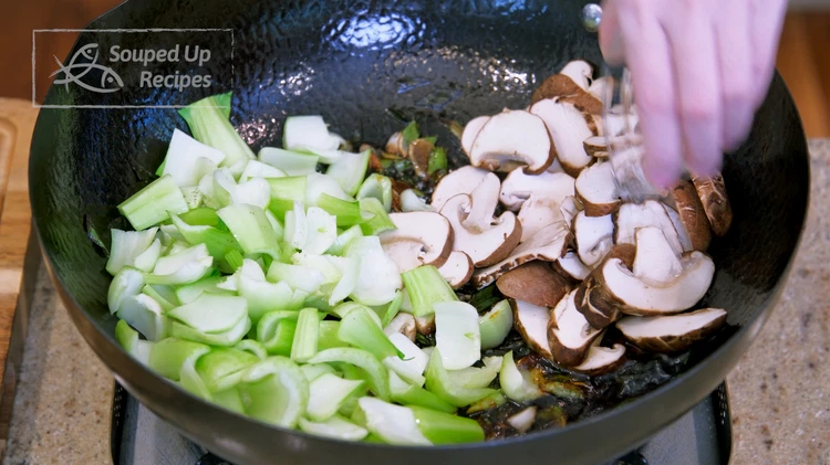 Image of Toss in the bok choy stems and mushroom slices. Drizzle a splash of water from the side of wok. The scallion and garlic are already camelized, so the water here will prevent them from burning. Keep stirring over medium-low heat...