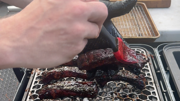 Image of Once your ribs hit 185 degrees internal, set your grill up for a hot session. Move your bones from your smoker to your grill and baste all sides twice with your marinade