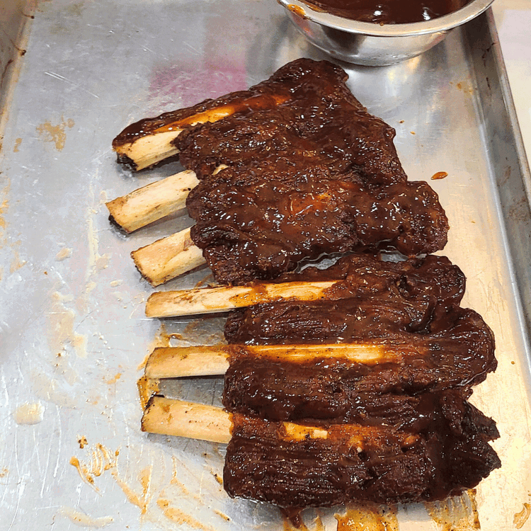 Image of Apply BBQ Sauce: After 2 hours of being wrapped, carefully unwrap the ribs. Brush BBQ sauce generously over both sides of the ribs.