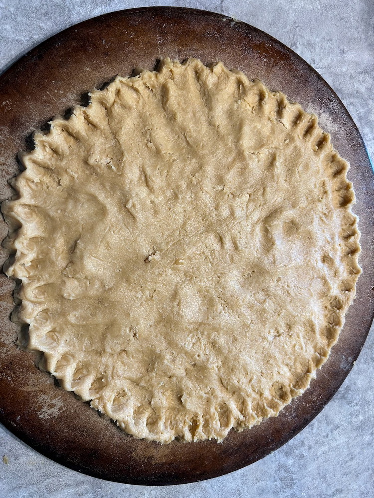 Image of The dough should make two 12” pizza-size tarts. You can roll out the dough like pie dough or press it out on the pan with floured fingers. Once the dough is evenly distributed, flute the edges (To flute the edges...