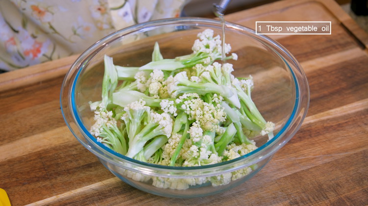 Image of Cut the cauliflower into small florets. Add a drizzle of vegetable oil and stir to coat well. 