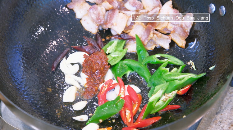 Image of Add the garlic slices, diced Thai bird eye chilies, green chili, dried red chilies, and Sichuan dou ban jiang (Using different kinds of spicy ingredients makes the flavor more complex). Stir over medium-low heat for a couple of minutes to...